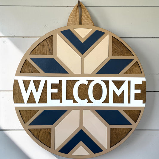 Wooden 'Welcome' sign with geometric patterns on a white wooden background