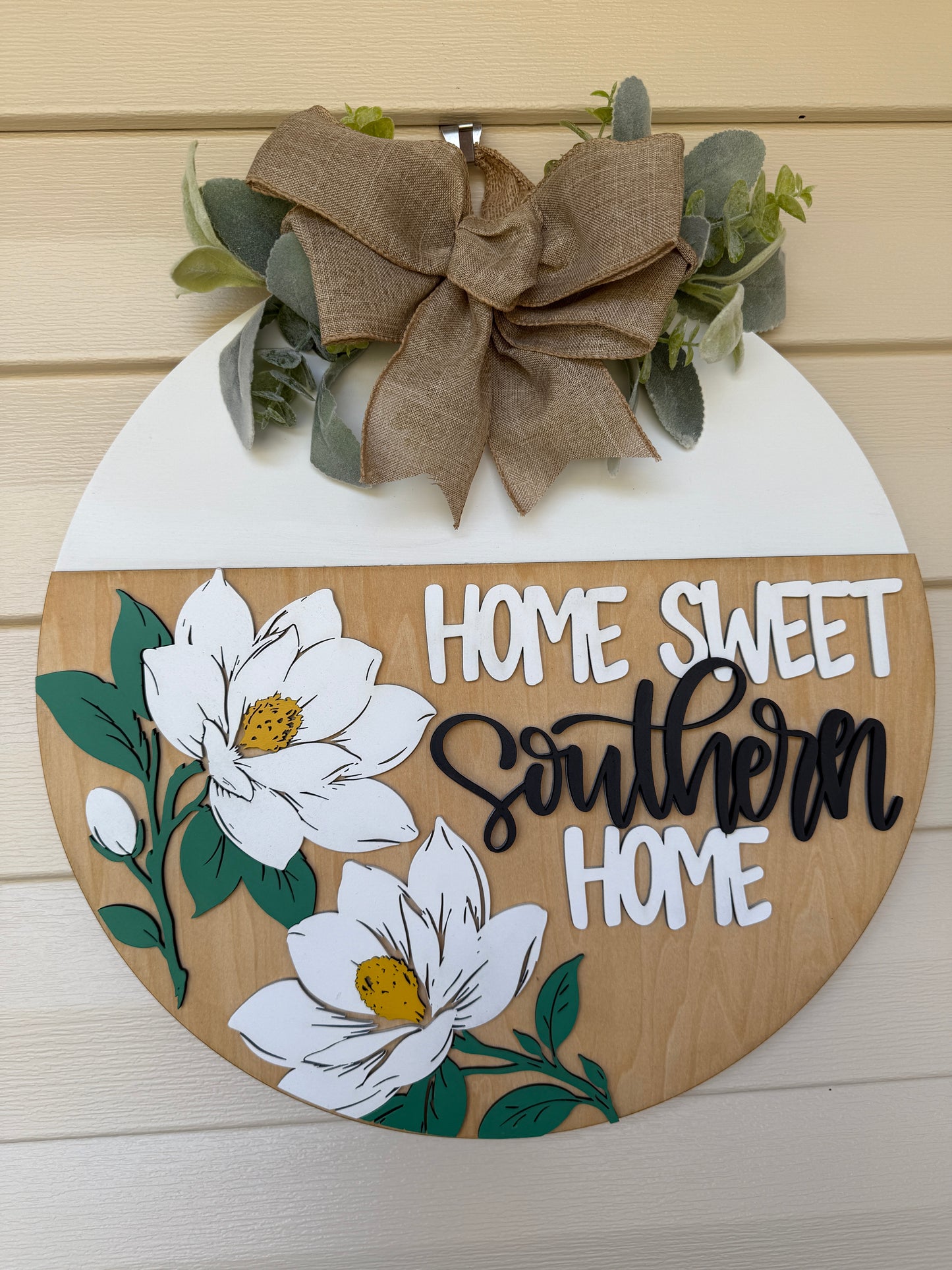 Decorative sign with 'Home Sweet Southern Home' text, flowers, and a bow on a wooden background.