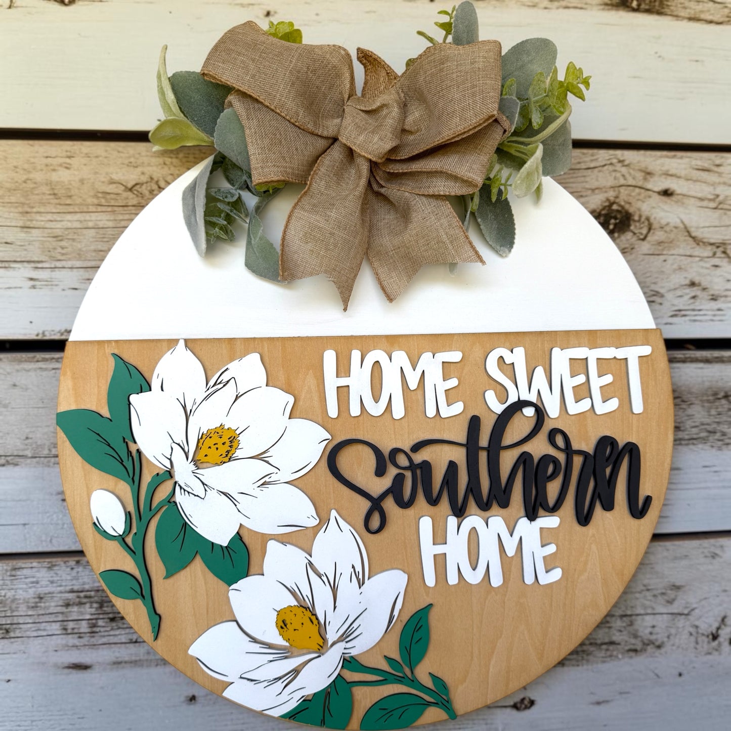 Decorative sign with 'Home Sweet Southern Home' text, flowers, and a bow on a wooden background.
