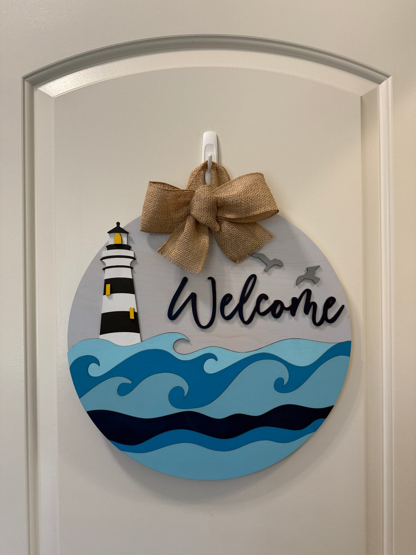Decorative door hanger featuring a lighthouse and waves design, by Covered Bridge Workshop, perfect for coastal or nautical decor.