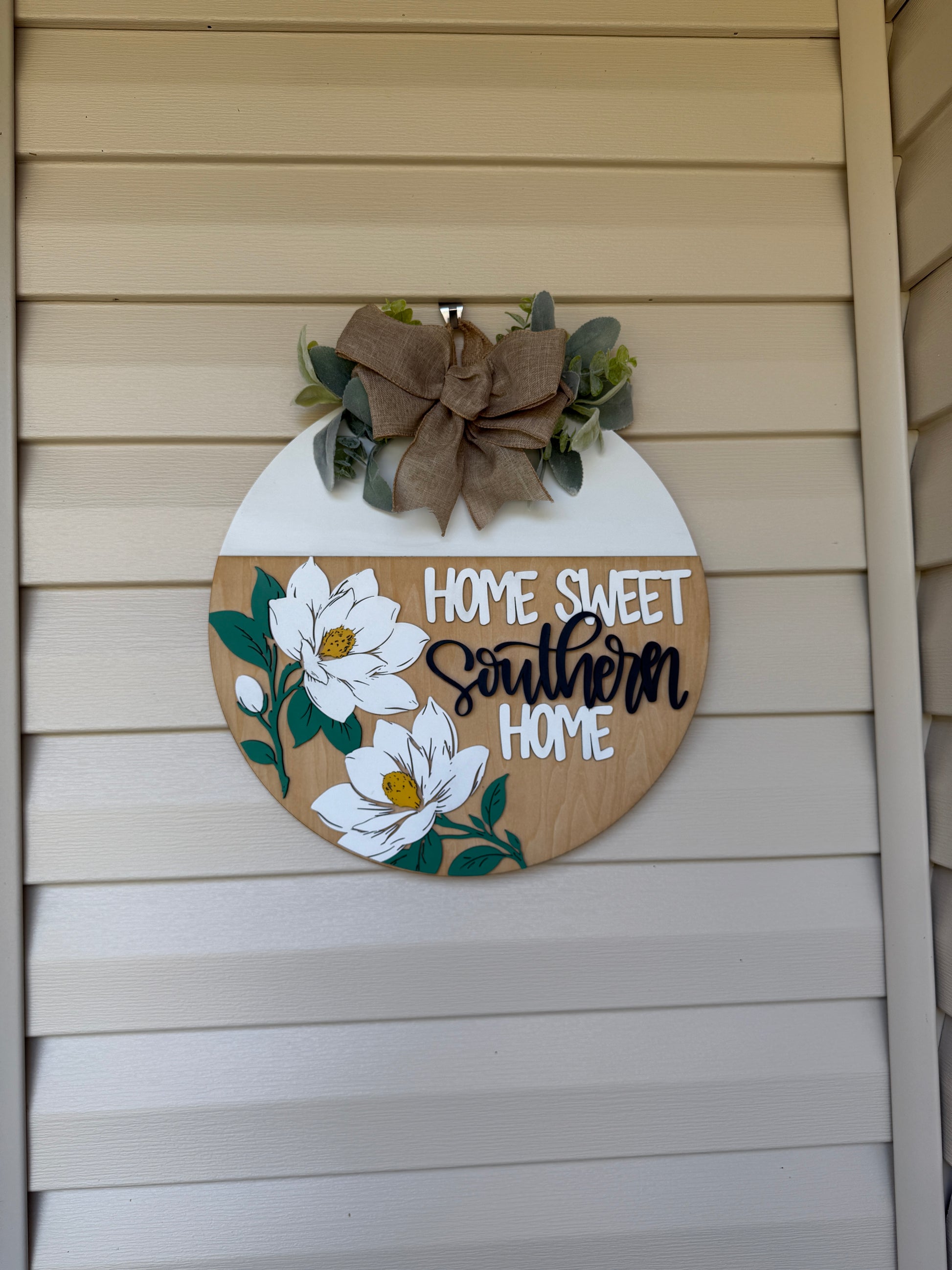 Decorative sign with 'Home Sweet Southern Home' text and floral designs on a wooden surface.