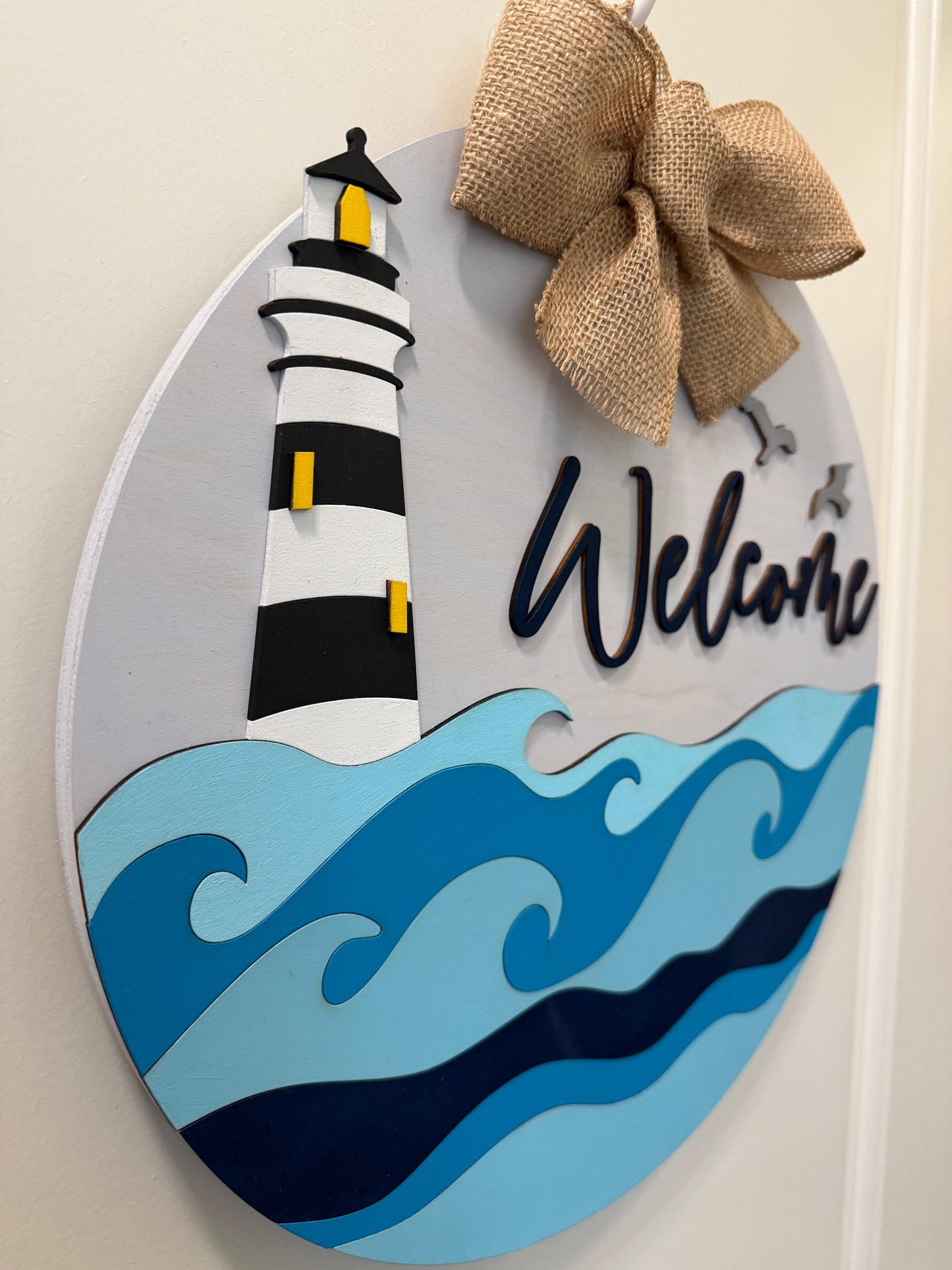 Decorative door hanger featuring lighthouse and ocean wave design by Covered Bridge Workshop for coastal home decor.