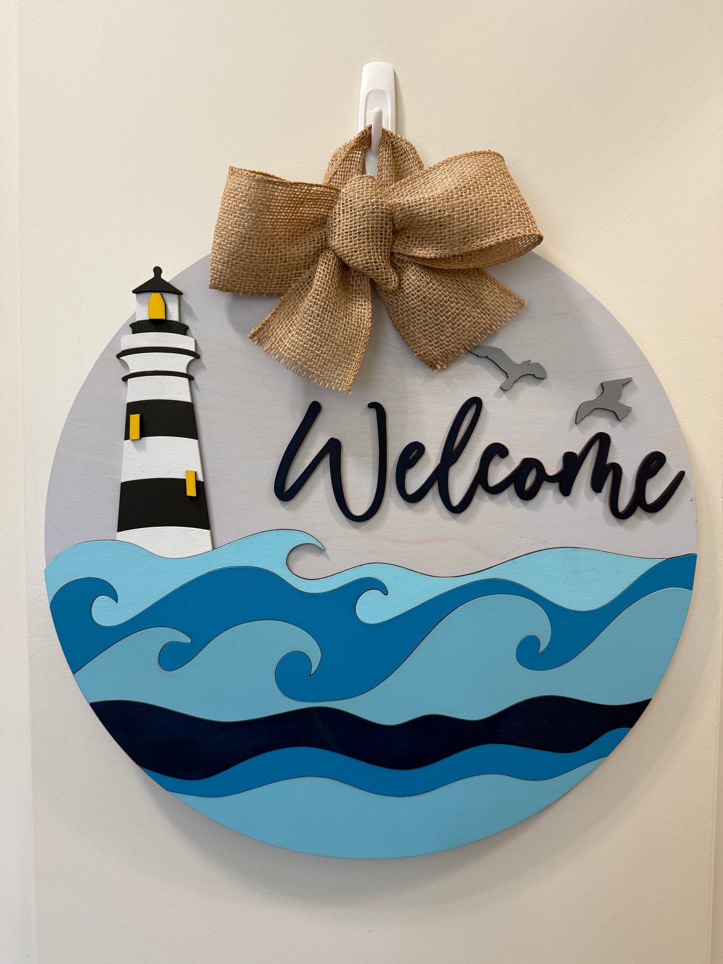 Decorative door hanger featuring lighthouse and waves design by Covered Bridge Workshop, perfect for coastal or nautical home decor.