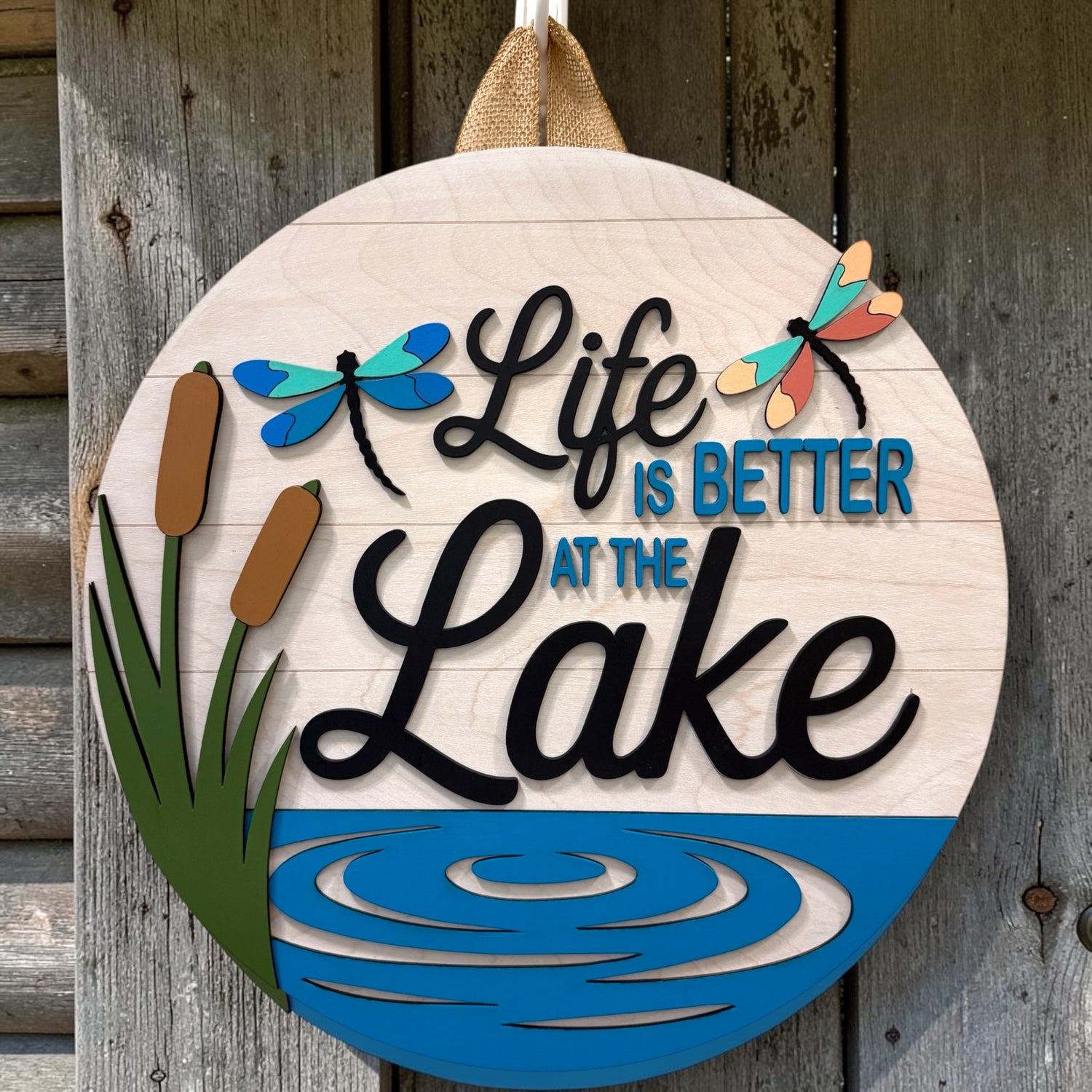 Decorative sign with 'Life is Better at the Lake' text on a wooden background
