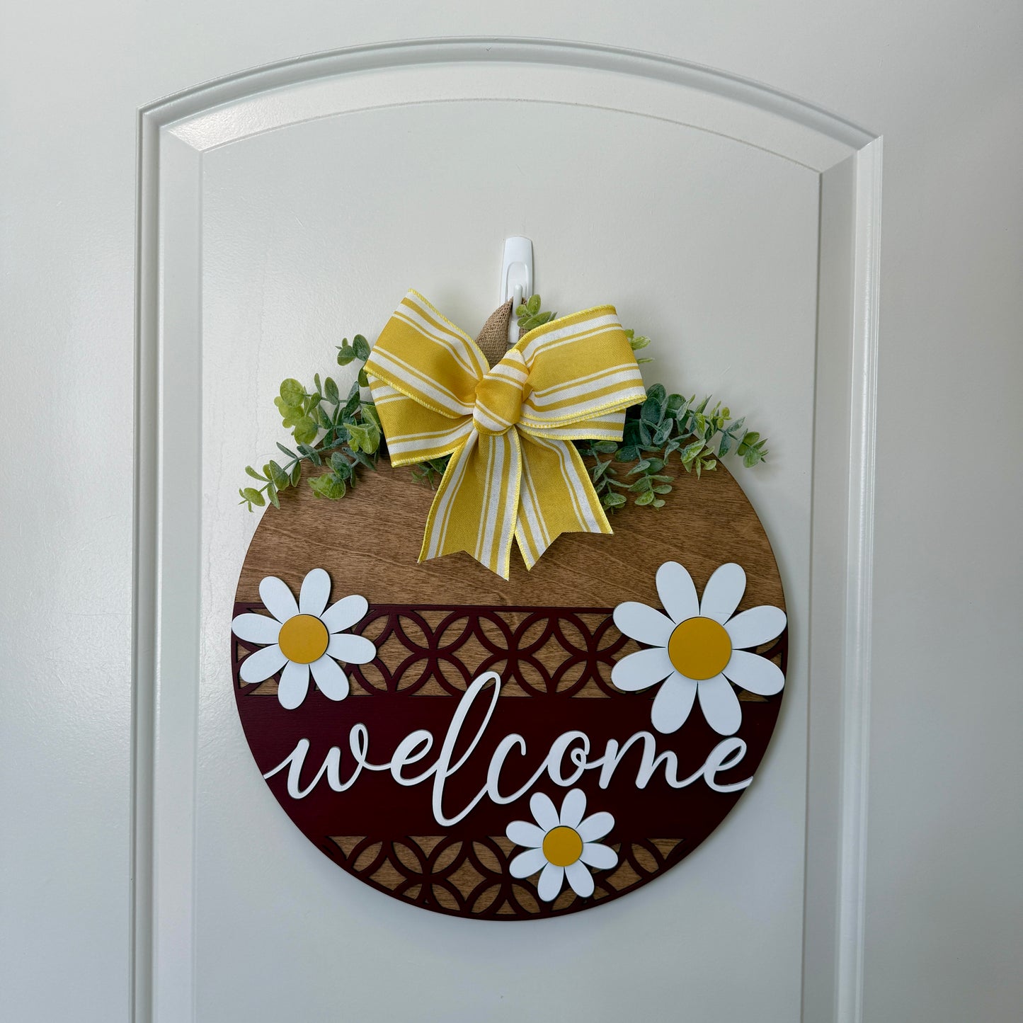 Decorative door hanger featuring a welcome message and daisy design from Covered Bridge Workshop, perfect for front door decor.